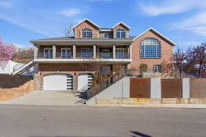 View of front of property with driveway, an attached garage, brick siding, and covered porch