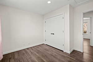 Unfurnished bedroom featuring dark wood-style floors, a closet, and recessed lighting