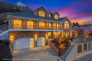 View of front facade with driveway, a garage, a porch, stone siding, and a shingled roof