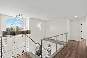 Hallway with wood finished floors and an upstairs landing