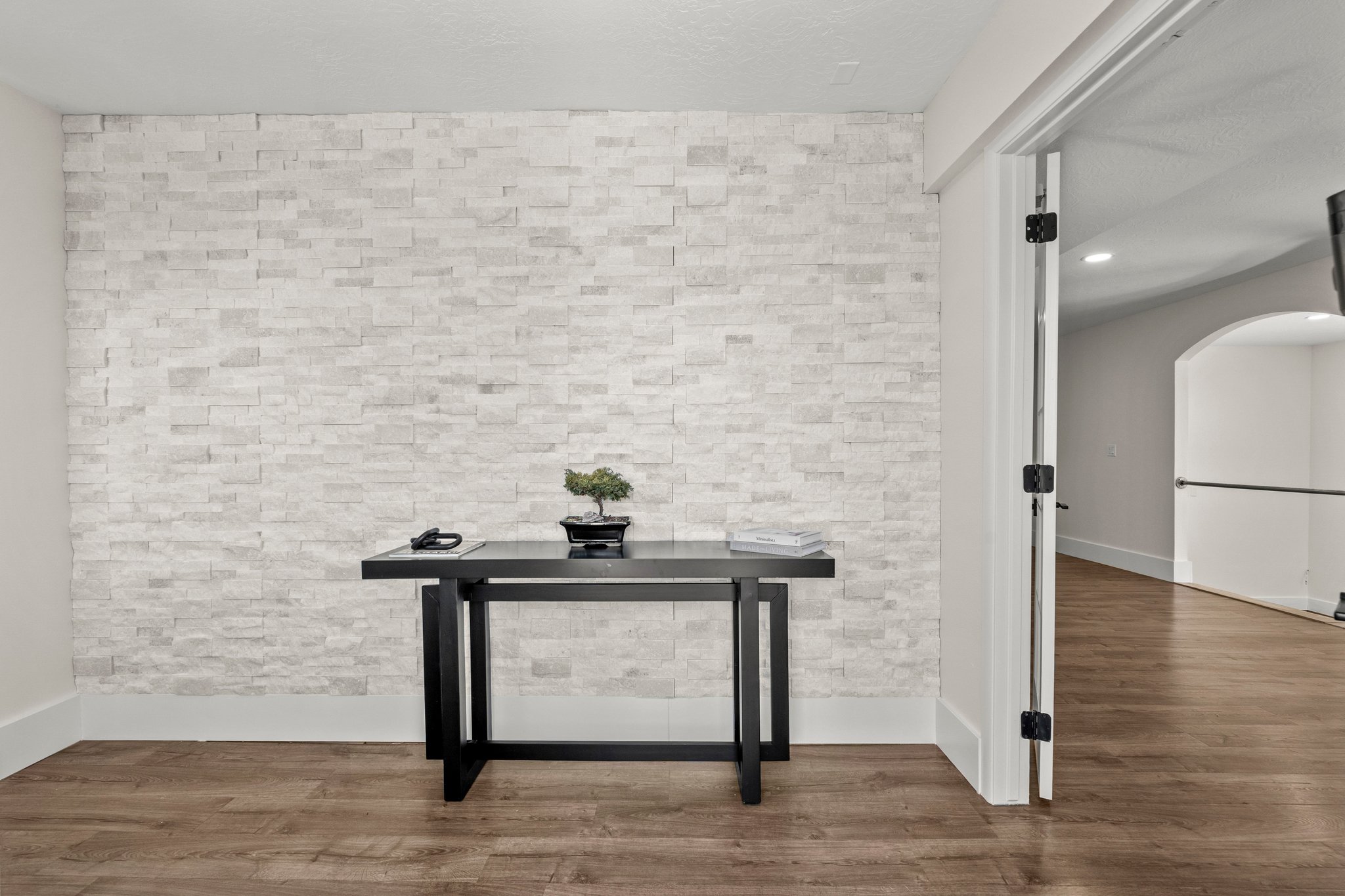 Detailed view of arched walkways, wood finished floors, an accent wall, and recessed lighting