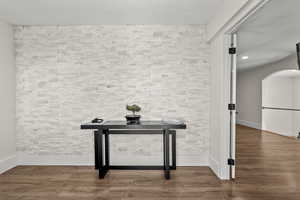 Detailed view of arched walkways, wood finished floors, an accent wall, and recessed lighting