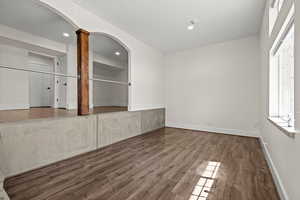 Unfurnished dining area featuring arched walkways, dark wood-type flooring, and decorative columns