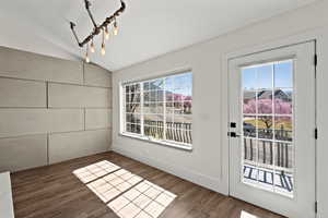 Doorway featuring wood finished floors and vaulted ceiling