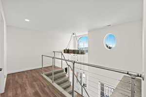 Hall featuring dark wood-style flooring, recessed lighting, and an upstairs landing