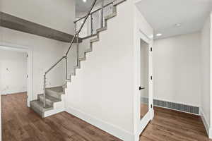 Staircase featuring wood finished floors and recessed lighting