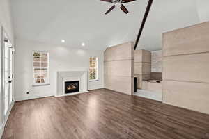 Unfurnished living room featuring a glass covered fireplace, dark wood-style floors, vaulted ceiling, a ceiling fan, and recessed lighting