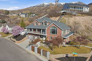 View of front of home with a balcony, a mountain view, concrete driveway, a garage, and brick siding
