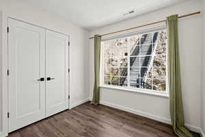 Unfurnished bedroom with dark wood-style flooring and a closet