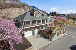 View of front of house with an attached garage, concrete driveway, a balcony, and stone siding