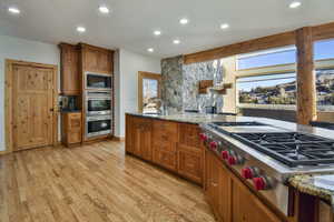 Kitchen with stainless steel appliances, wood finish cabinetry, light stone countertops, light wood-style flooring, and recessed lighting