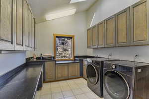 Laundry room featuring vaulted ceiling, cabinet space, independent washer and dryer, and light tile patterned flooring