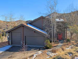 View of front facade featuring stone siding, concrete driveway, a garage, and a mountain view