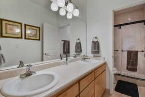 Full bathroom featuring a shower stall, double vanity, and light tile patterned flooring