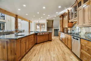 Kitchen featuring dark stone counters, wood finish cabinets, light wood-style flooring, stainless steel appliances, and recessed lighting