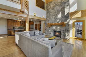 Living room featuring a high ceiling, light wood-style flooring, a fireplace, and recessed lighting