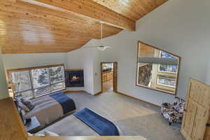 Bedroom featuring light colored carpet, a high wooden beamed ceiling, a ceiling fan, and a fireplace