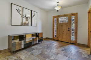 Entrance foyer with stone tile flooring and baseboards