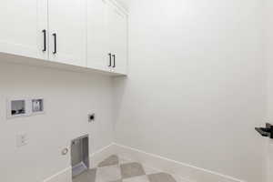 Laundry room with cabinet space, hookup for an electric dryer, washer hookup, light floors, and gas dryer hookup