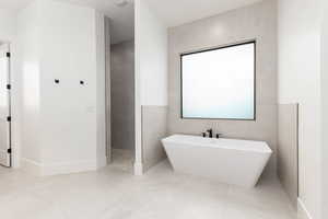 Full bath with a soaking tub, tile walls, walk in shower, and light tile patterned floors