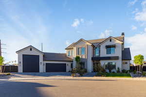View of front of home with stucco siding, a garage, driveway, and a chimney