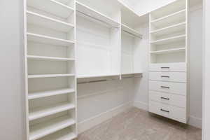 Walk in closet featuring light colored carpet