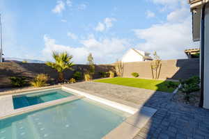 Integrated pool / hot tub with a fenced backyard and a patio