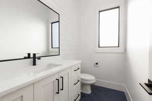 Half bath with vanity and dark tile patterned flooring