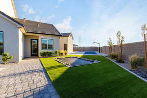 Fenced backyard featuring a patio and basketball court