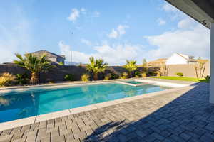 Integrated pool / hot tub with a fenced backyard and a patio area