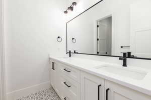 Full bathroom featuring double vanity and baseboards