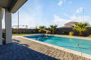 View of swimming pool with patio surround and a fenced backyard