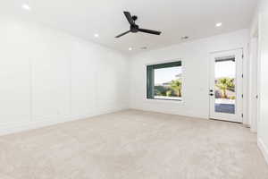 Unfurnished room featuring light colored carpet, a decorative wall, a ceiling fan, and recessed lighting
