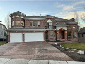 View of front of property featuring an attached garage, decorative driveway, and brick siding