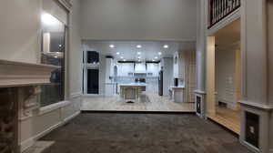 Living room featuring a high ceiling, light colored carpet, recessed lighting, and a decorative wall