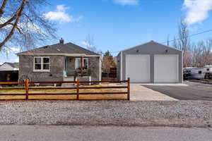 Single story home with an outbuilding, brick siding, a fenced front yard, a chimney, and a detached garage