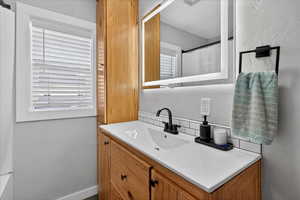 Bathroom with vanity, a shower with curtain, a textured wall, and decorative backsplash