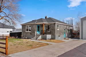 Bungalow-style house with brick siding, an outbuilding, a chimney, and roof with shingles