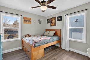 Bedroom with wood finished floors, a ceiling fan, and a textured wall