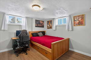 Bedroom featuring wood finished floors, a textured ceiling, and a desk