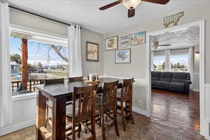 Dining area with wainscoting, a textured ceiling, ceiling fan, and stone finish flooring