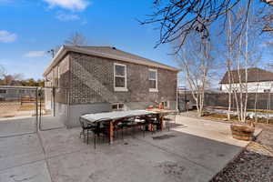Rear view of property with a gate, outdoor dining area, brick siding, a fenced backyard, and a patio area