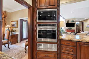 Kitchen featuring oven, light stone counters, a warming drawer, built in microwave, and open floor plan