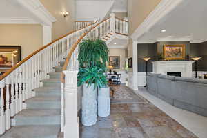 Stairs with wainscoting, a fireplace, ornamental molding, a decorative wall, and stone finish flooring