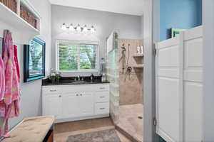 Bathroom with vanity, walk in shower, and light tile patterned flooring