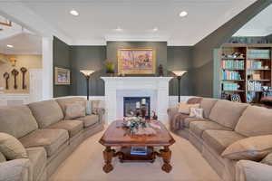 Living room featuring wainscoting, crown molding, a premium fireplace, recessed lighting, and carpet floors
