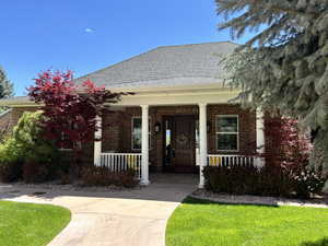 View of front of house with brick siding, covered porch, and a shingled roof