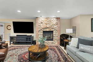 Living room featuring a stone fireplace and recessed lighting