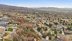 Aerial perspective of suburban area featuring property boundaries highlighted and a mountain backdrop