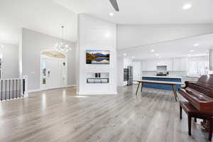 Living room featuring vaulted ceiling, suspended lighting, light wood-type flooring, and a ceiling fan